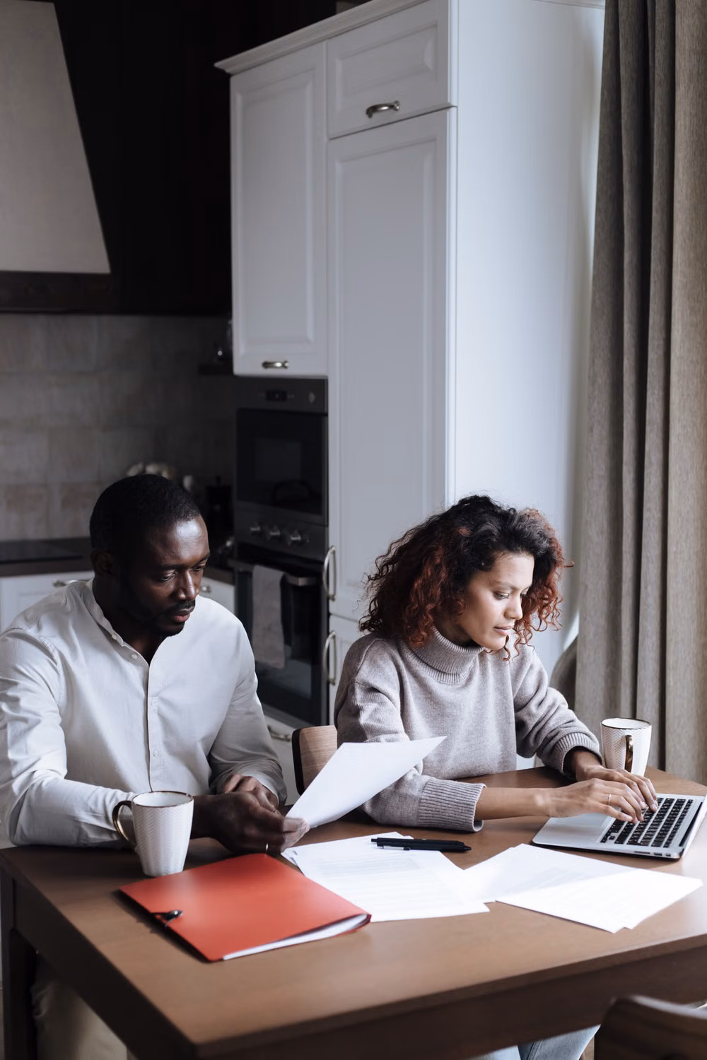 A couple reviewing documents and a laptop at their kitchen table